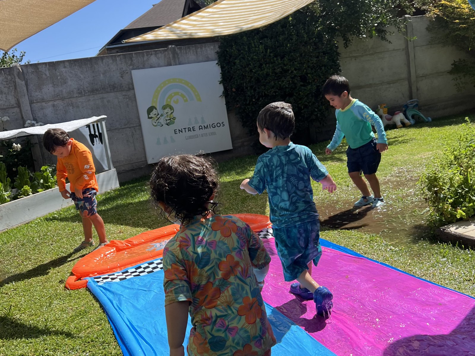 Niños y niñas disfrutando juegos de agua al aire libre en Entre Amigos